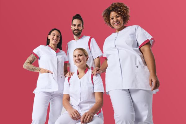 Drei Frauen und ein Mann tragen ein Teamoutfit in weiß für Pfleger.